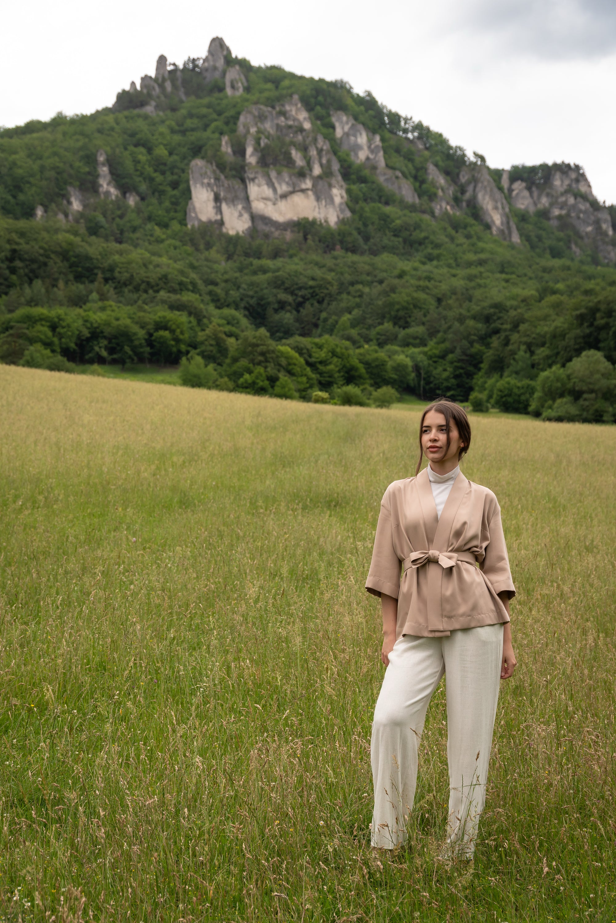 Woman wearing kimono, standing in a field with mountains in the background