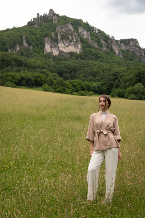 Woman wearing kimono, standing in a field with mountains in the background