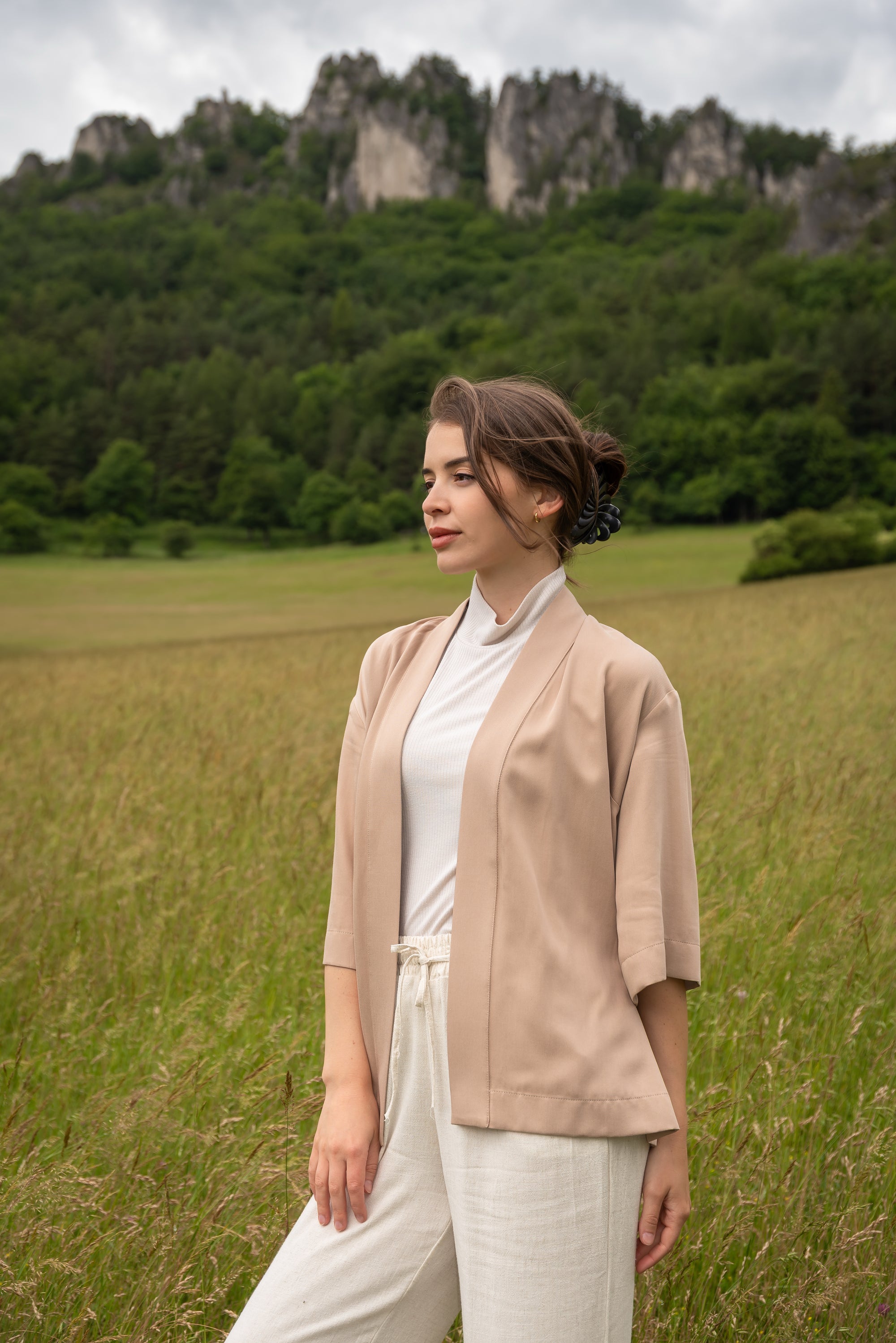 Woman wearing kimono, standing in a field with mountains in the background