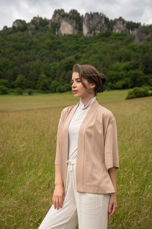 Woman wearing kimono, standing in a field with mountains in the background
