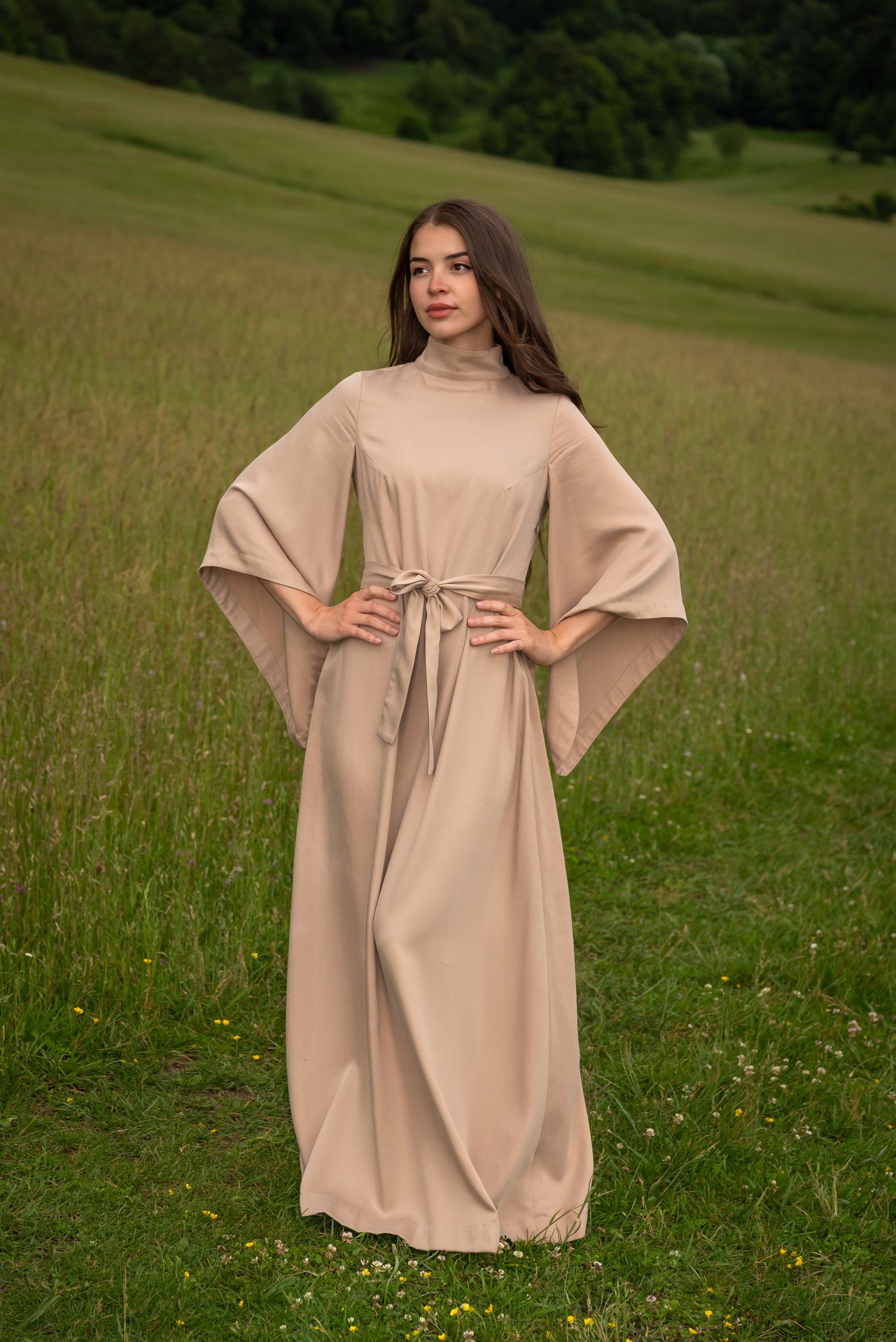 Woman in a beige dress standing in a grassy field